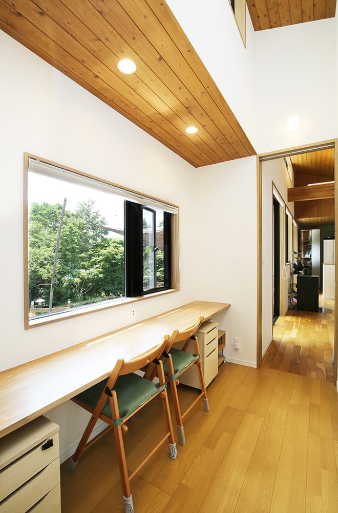 緑に開いた「くの字」の平屋の家