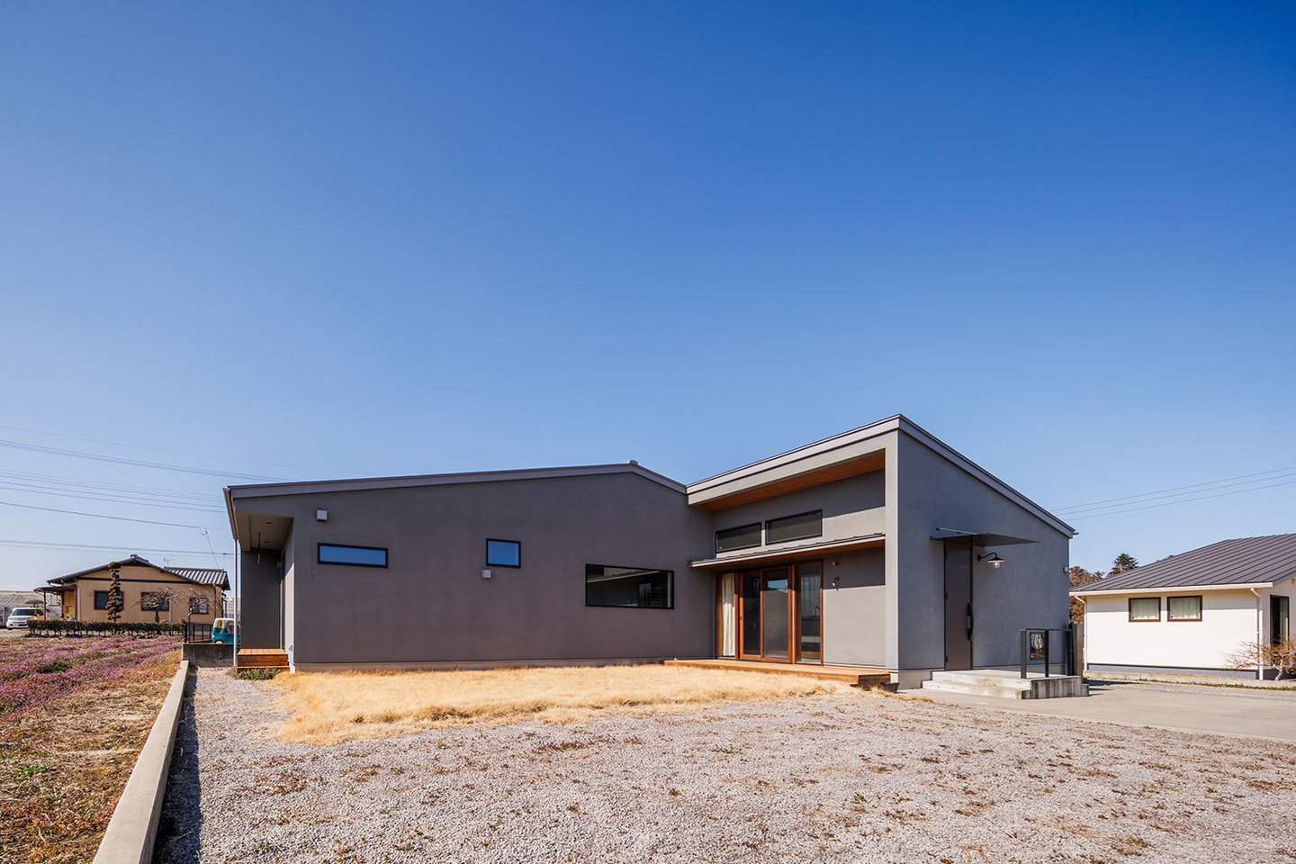 L型に配置したグレーと木が映える外観