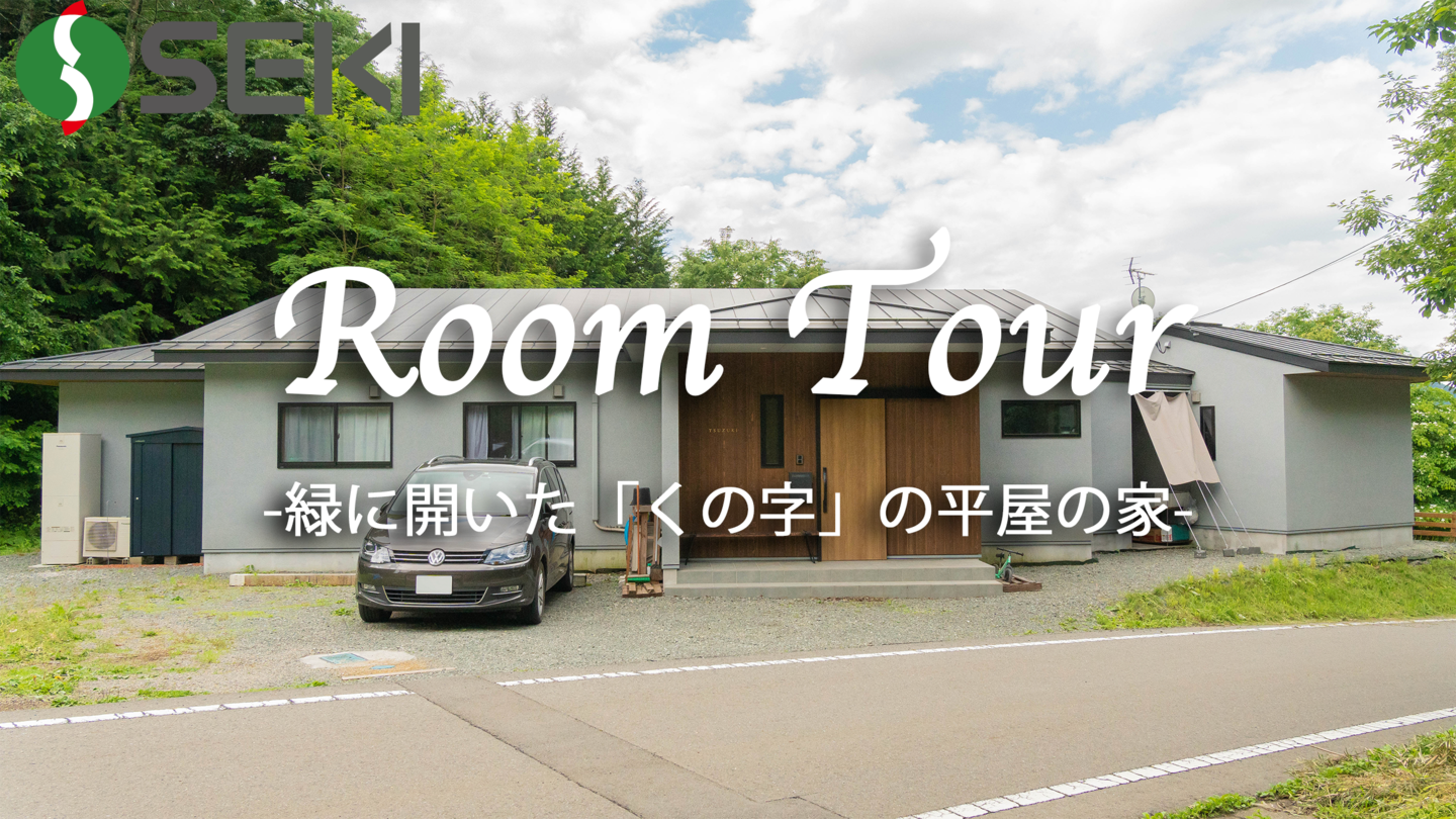 緑に開いた「くの字」の平屋の家
