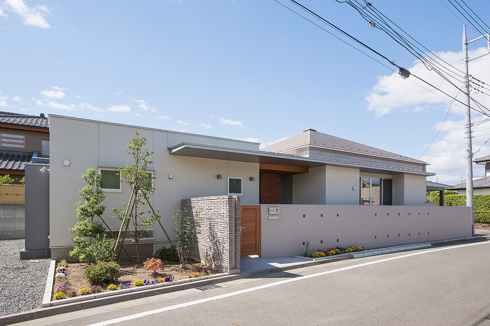 薄いピンクの外壁に囲まれている平屋の家